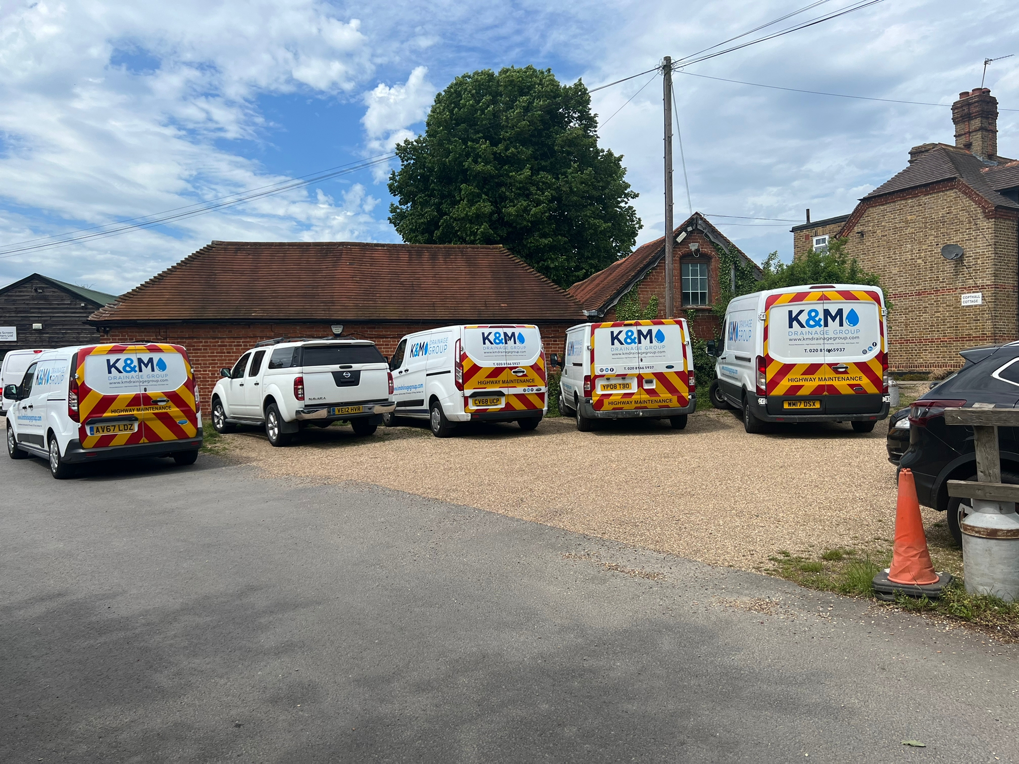 Row of K&M Drainage branded vans lined up at the yard